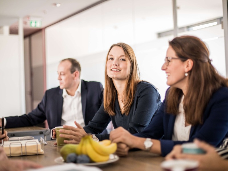 Photo of three adesso employees sitting at a table